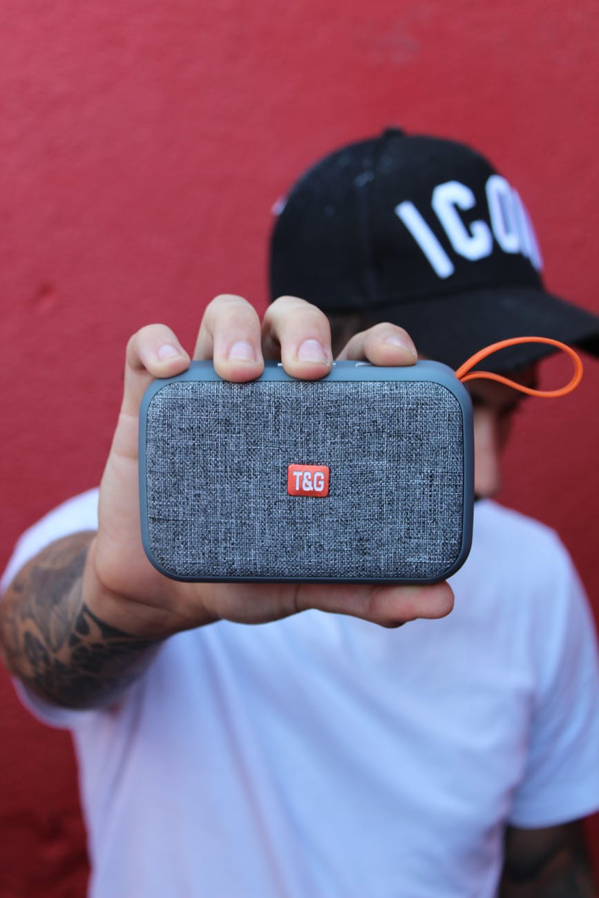 a person holding a gray portable speaker
